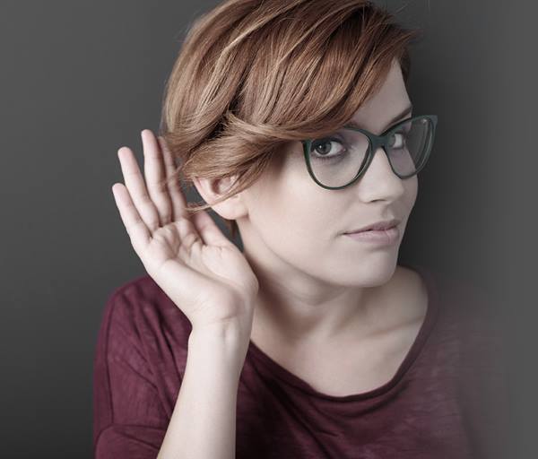 Femme qui essaie d'entendre la main derrière l'oreille